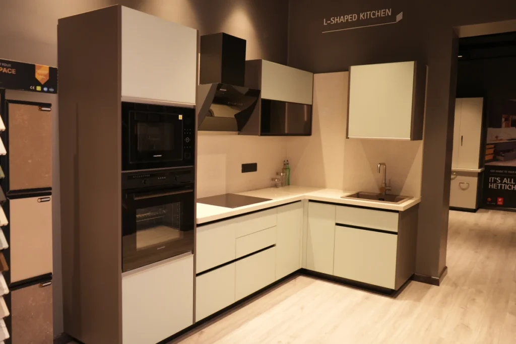 Modular Kitchen Designs 9 L-shaped modular kitchen with white cabinets and built-in appliances.
